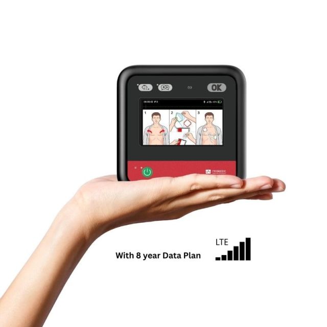 Primedic HeartSave myPAD fully automatic AED held in one hand, showing compact 15 x 15cm black and red device with colour LCD display