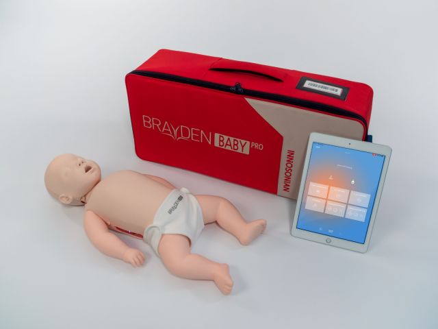 An infant CPR manikin showing the white illumination lights across the chest and forehead, which illuminate and show the direction of blood flow when effective CPR is being delivered. 